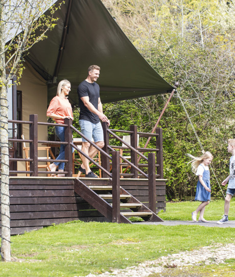 A family of four outside a safari lodge on Bowleaze Cove Holiday Park & Spa