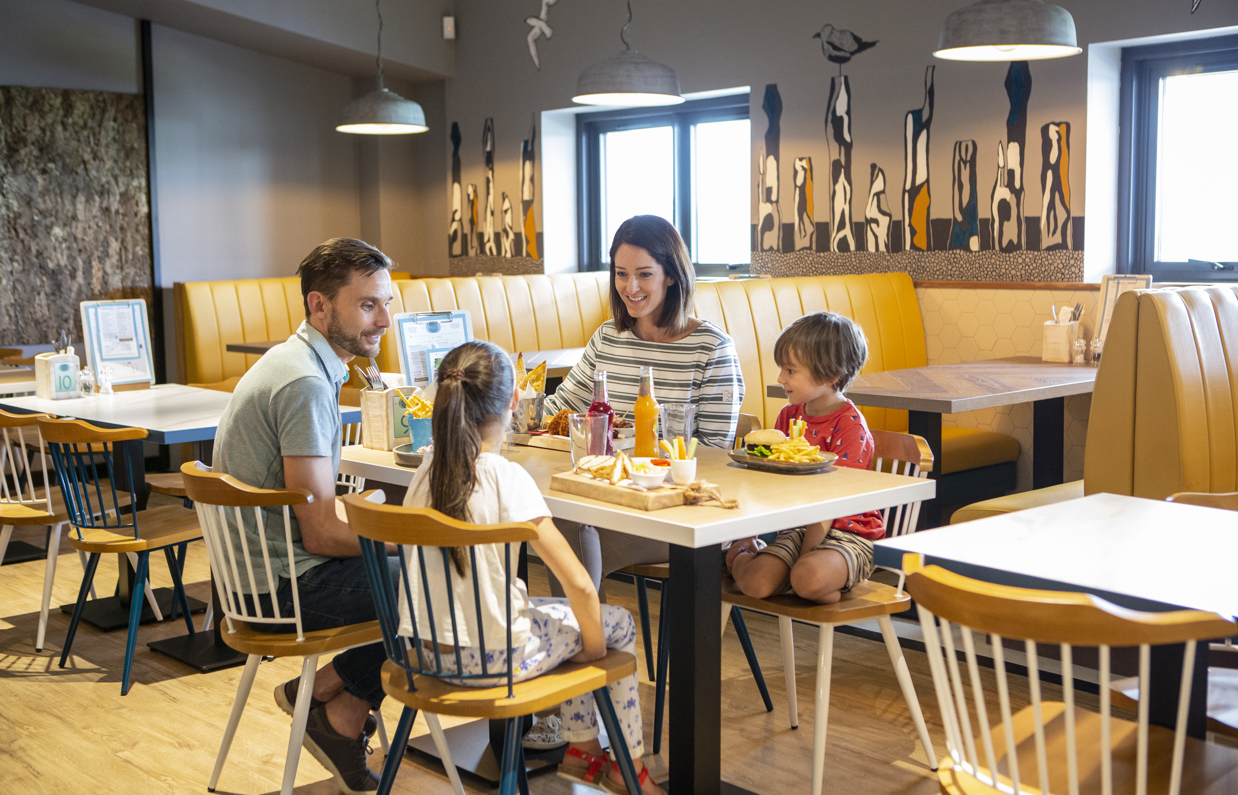 A couple with two children sat at a table in Breeze Bar & Grill with plates of food