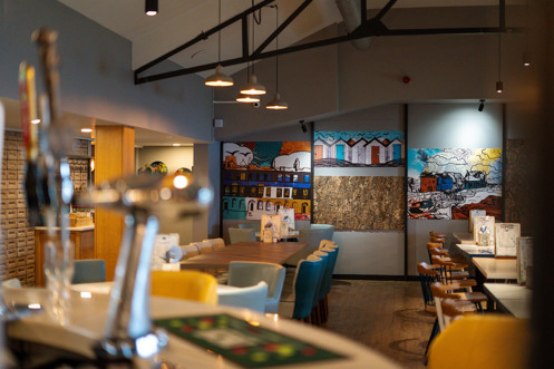 The internal of Breeze Bar & Grill from behind the bar with tables and chairs and draught