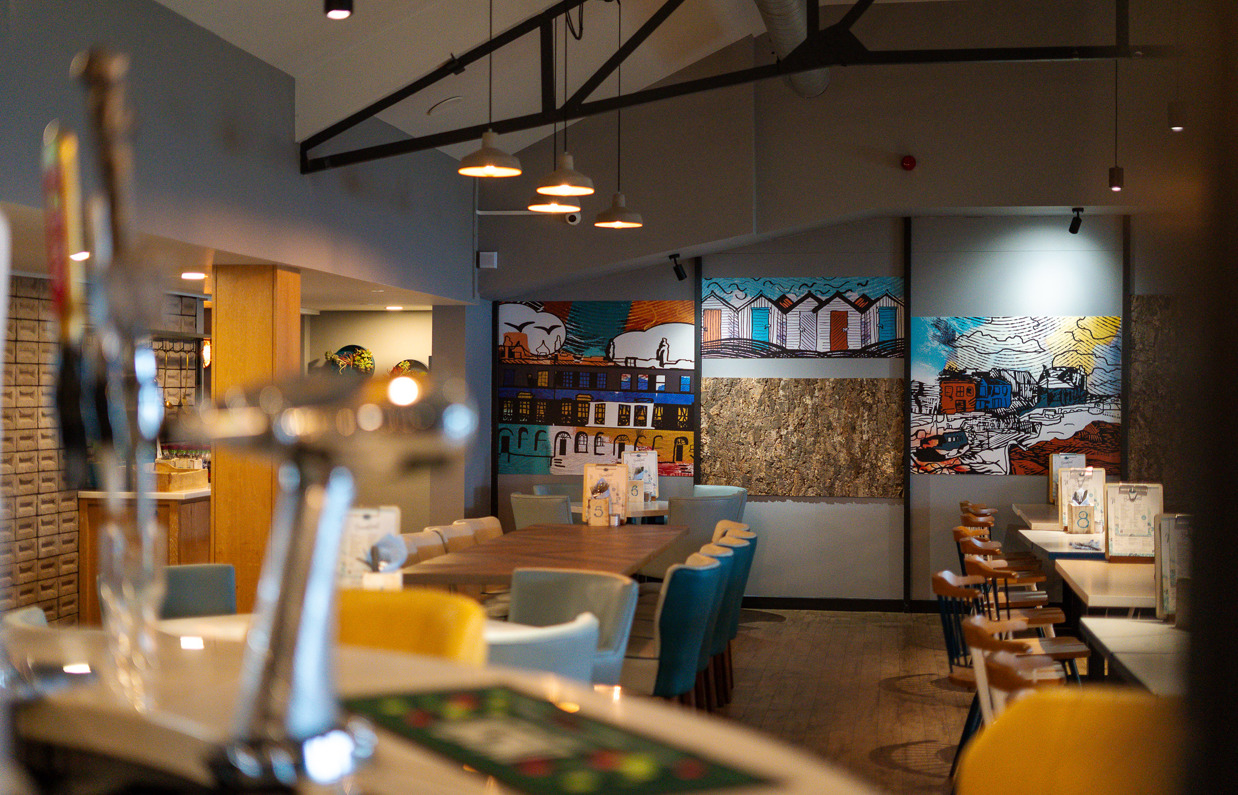 The internal of Breeze Bar & Grill from behind the bar with tables and chairs and draught