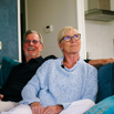 A couple sat smiling together on a sofa