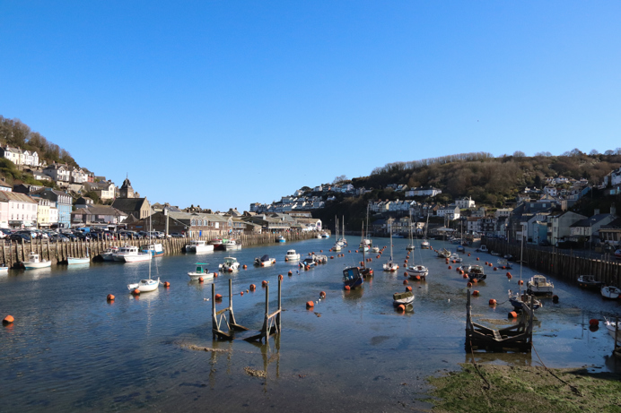 A harbour with various small boats, hills and houses on a sunny blue sky day