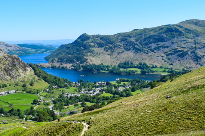 The view of the Lake District from high up with rolling hills, mountains and blue water