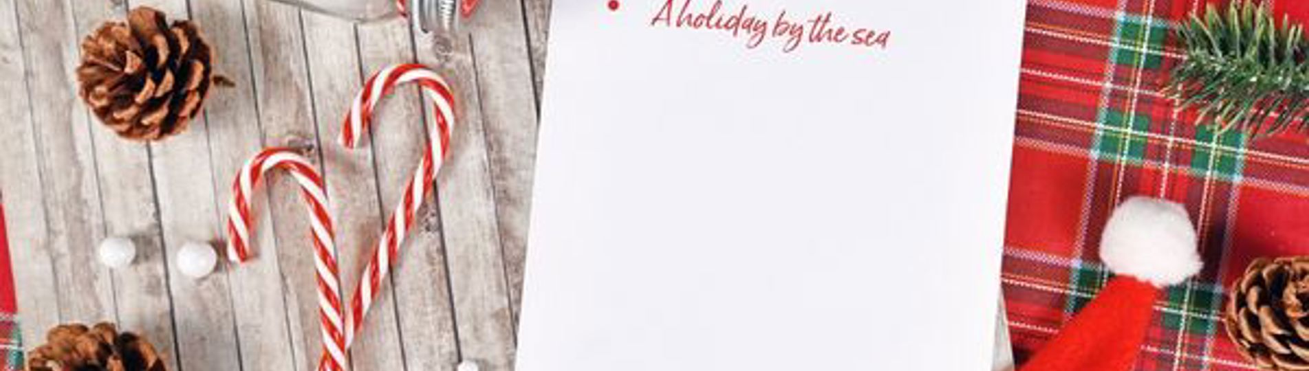 A Christmas table set from above with a wishlist on it with only one item: A holiday by the sea