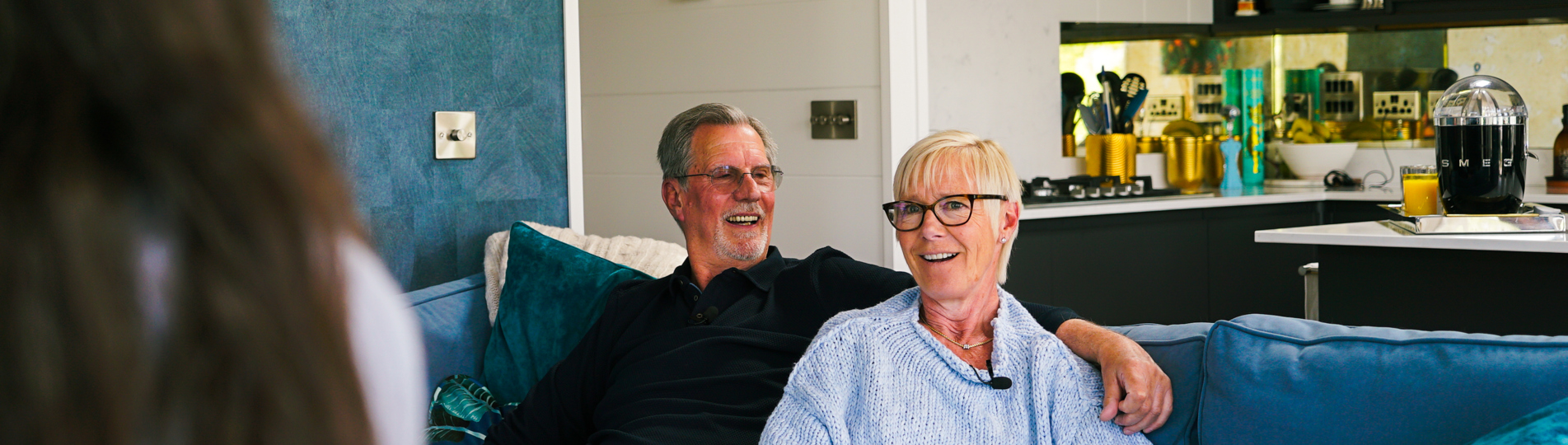 A couple sat on a sofa together looking at another woman