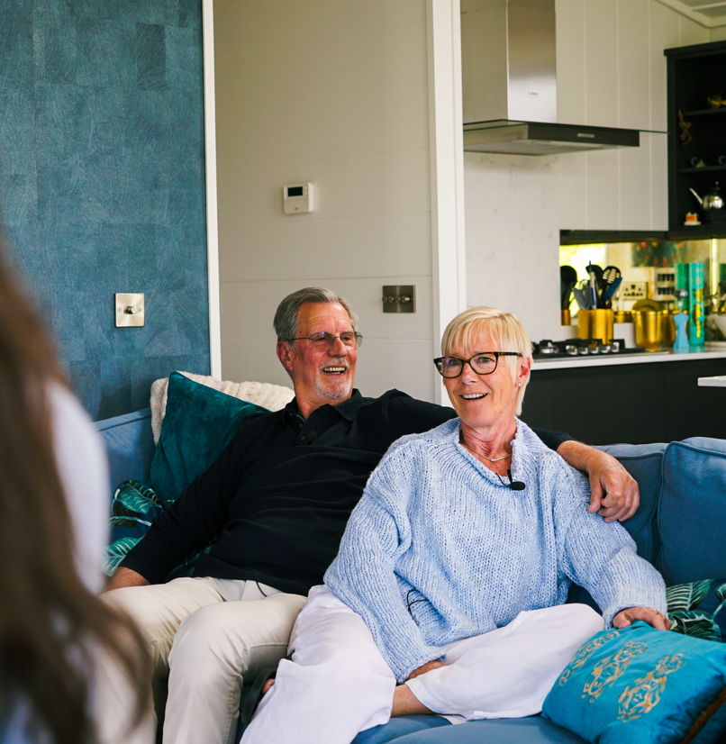 A couple sat on a sofa together looking at another woman