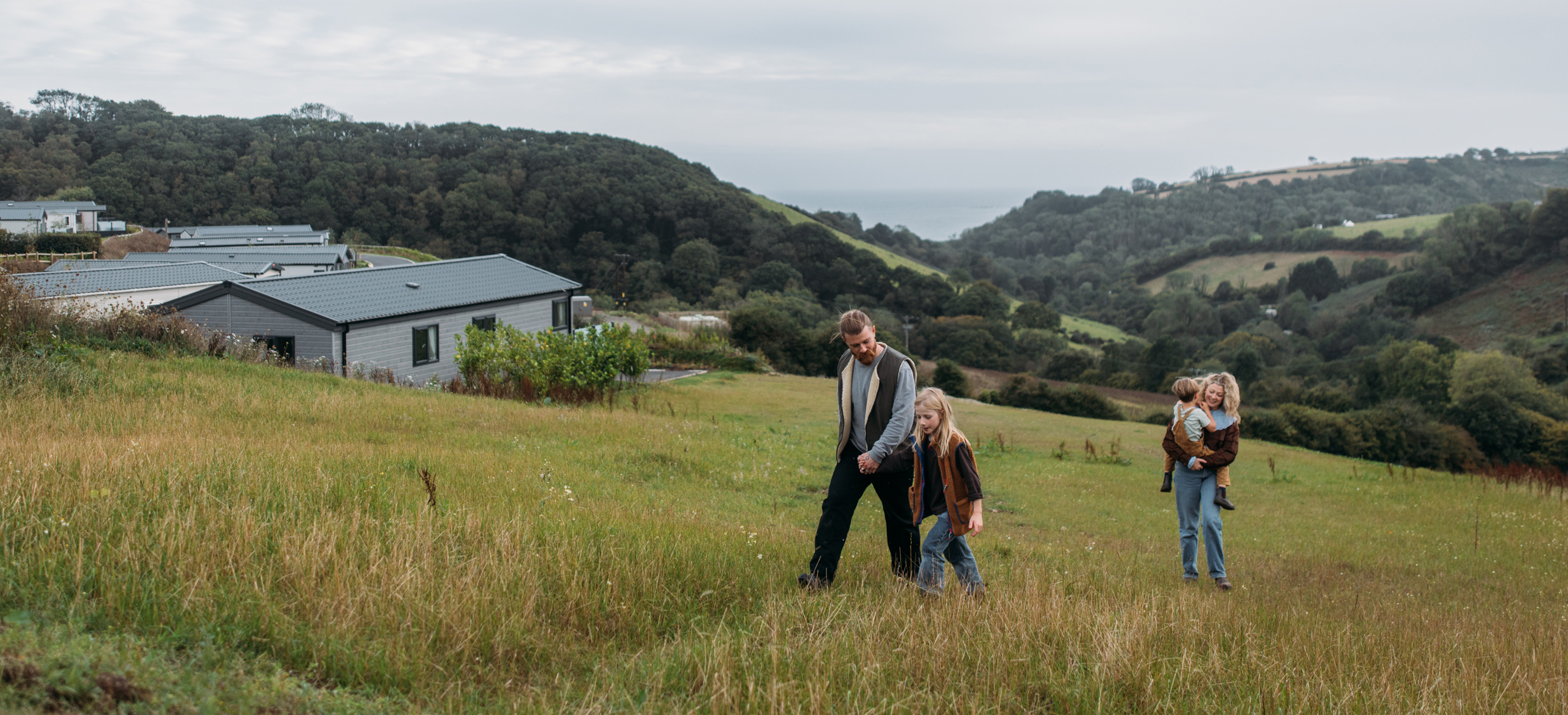 Family walking up hill at TG with valley and sea views behind them 
