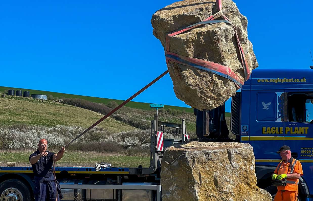Installation of a stone sculpture in a field with blue skies