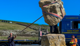 Installation of a stone sculpture in a field with blue skies