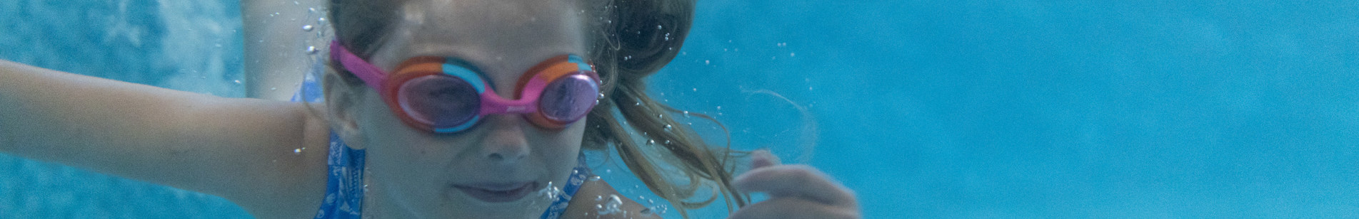 Girl swimming underwater with googles on