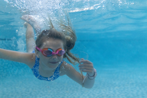 Girl swimming underwater with googles on