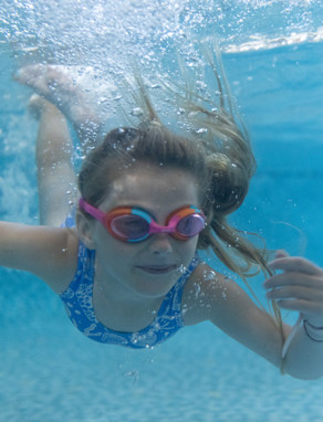 Girl swimming underwater with googles on
