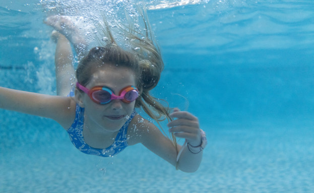 Girl swimming underwater with googles on