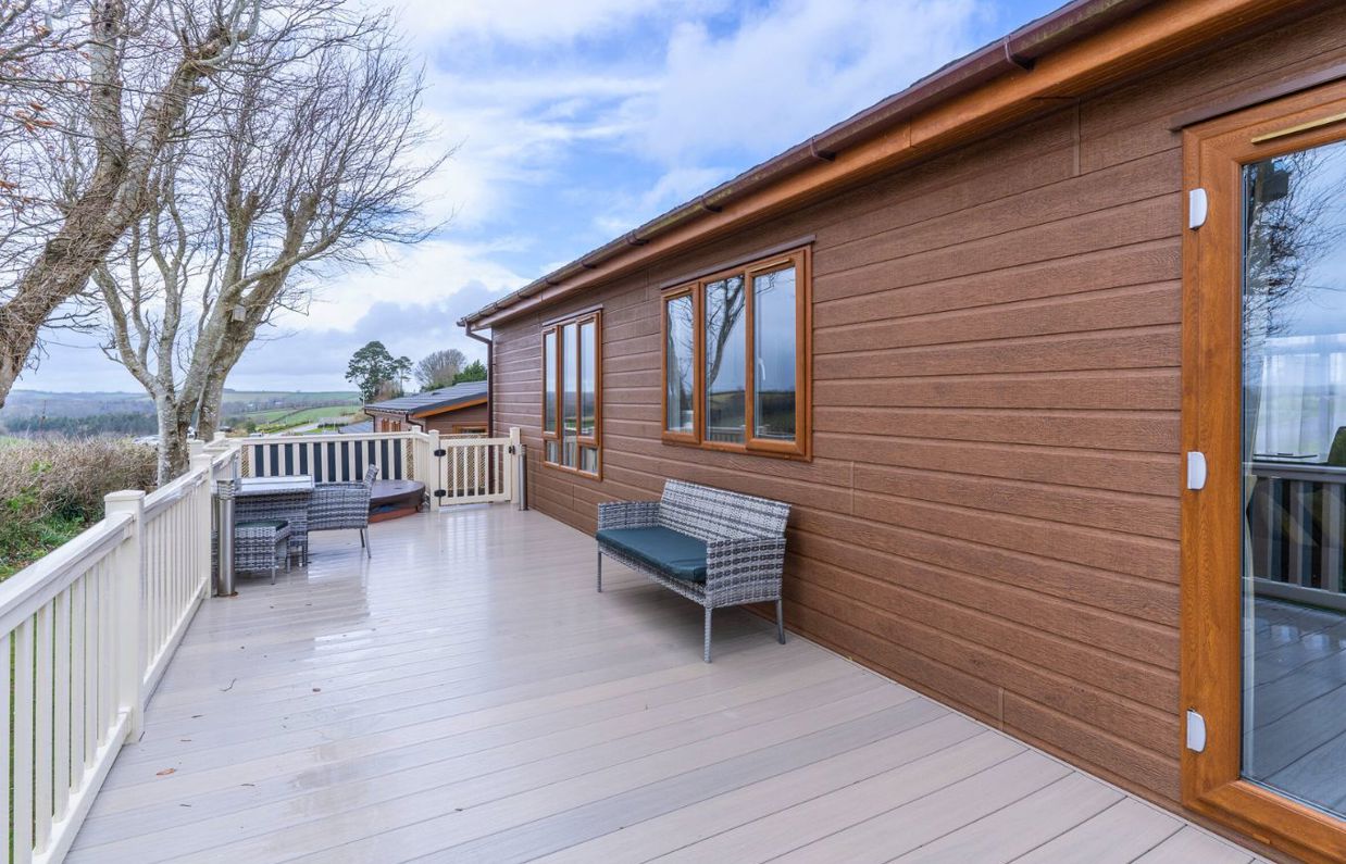 External of a lodge on pitch with decking, outdoor furniture and a sunken hot tub