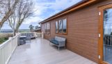 External of a lodge on pitch with decking, outdoor furniture and a sunken hot tub