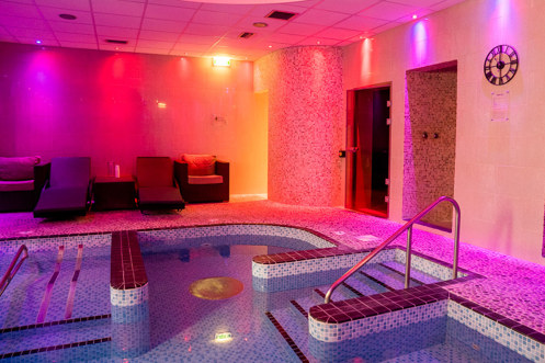 A hydrotherapy pool with loungers and calm lights