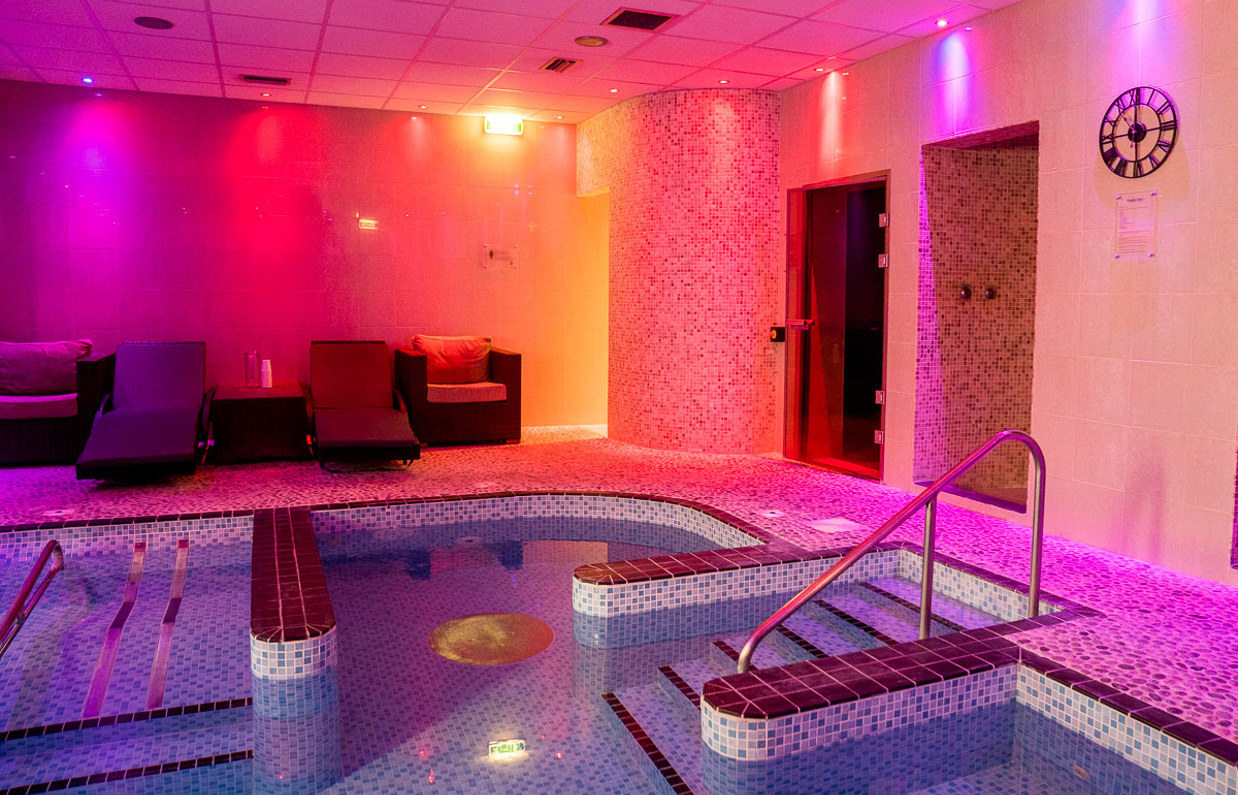 A hydrotherapy pool with loungers and calm lights