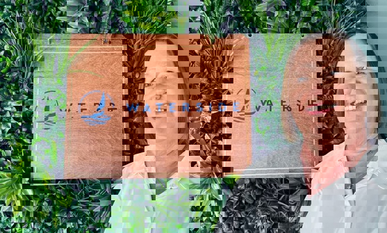 A smiling lady stood beside a Waterside sign