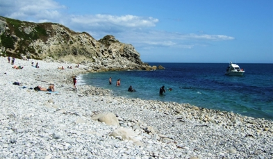 A cove with blue water at the bottom of a rocky hill