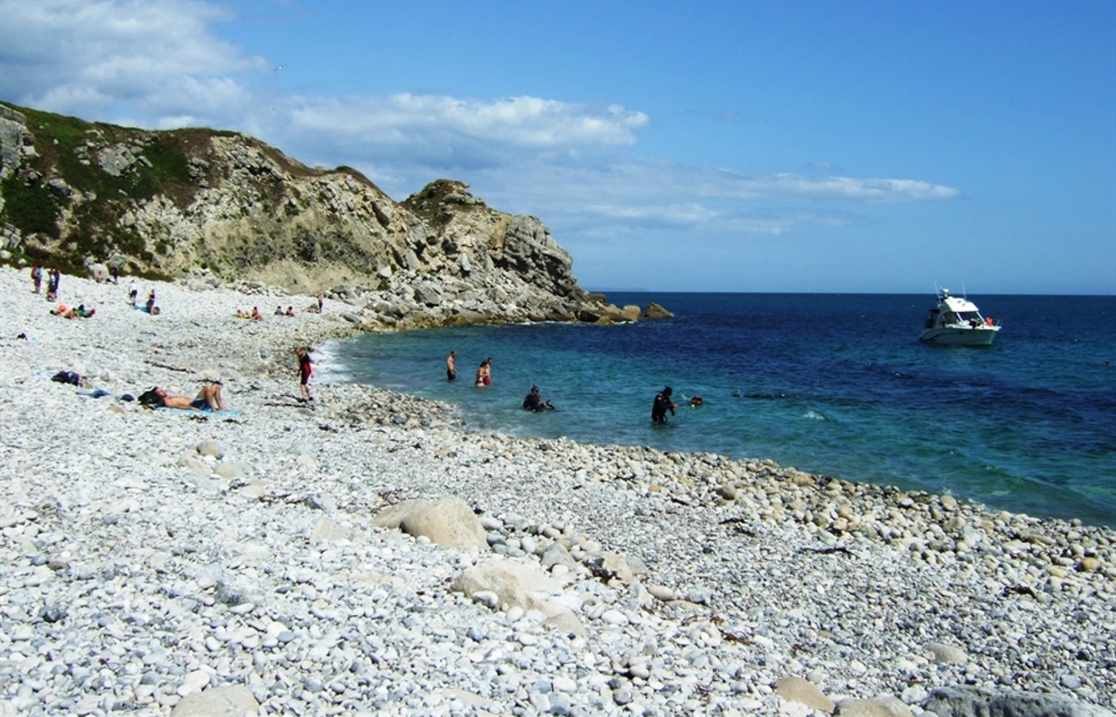 A cove with blue water at the bottom of a rocky hill