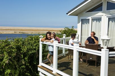 A family of four on the decking of a holiday home overlooking the sea
