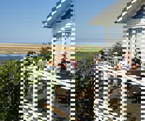 A family of four on the decking of a holiday home overlooking the sea