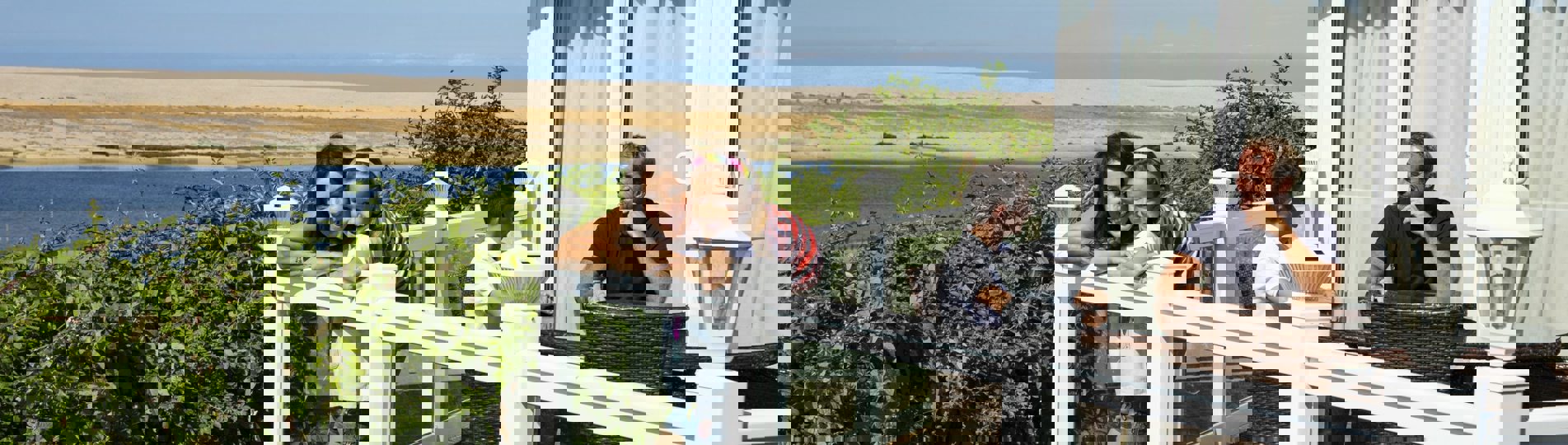 A family of four on the decking of a holiday home overlooking the sea