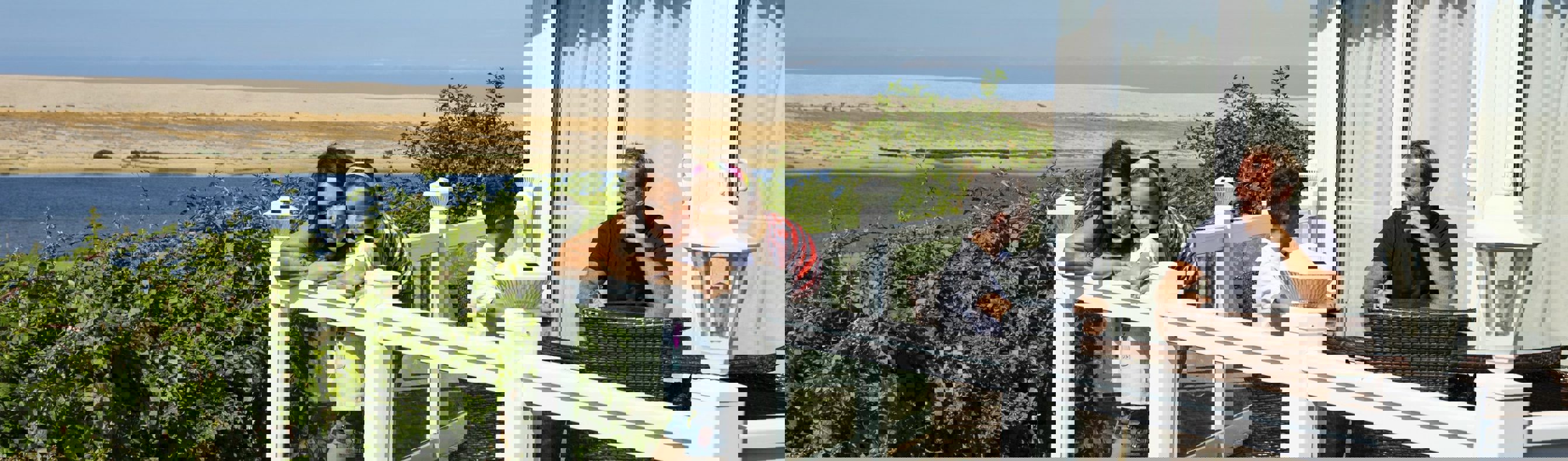 A family of four on the decking of a holiday home overlooking the sea