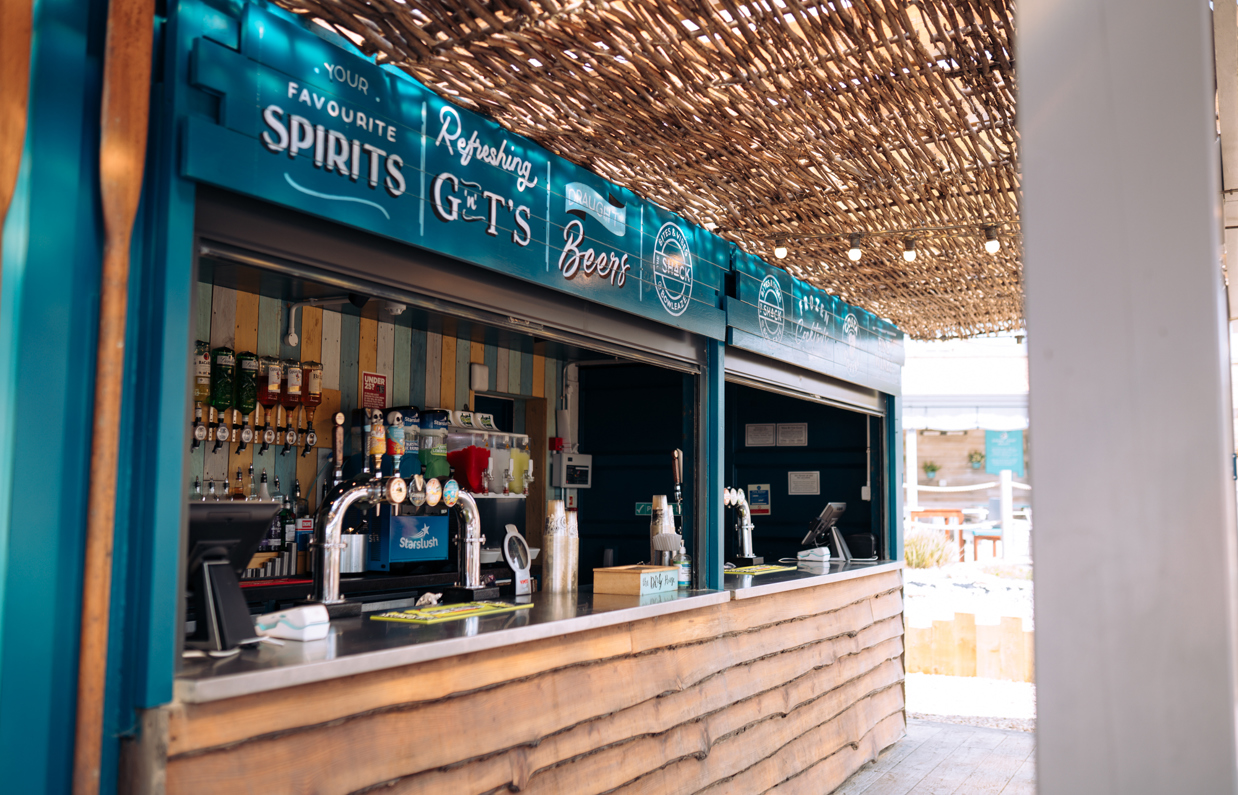 An outdoor beach drinks bar under cover with various draught, spirit and soft drinks on display