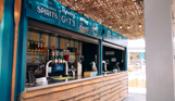 An outdoor beach drinks bar under cover with various draught, spirit and soft drinks on display