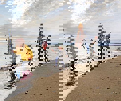 A family of four stepping across stones on the shoreline