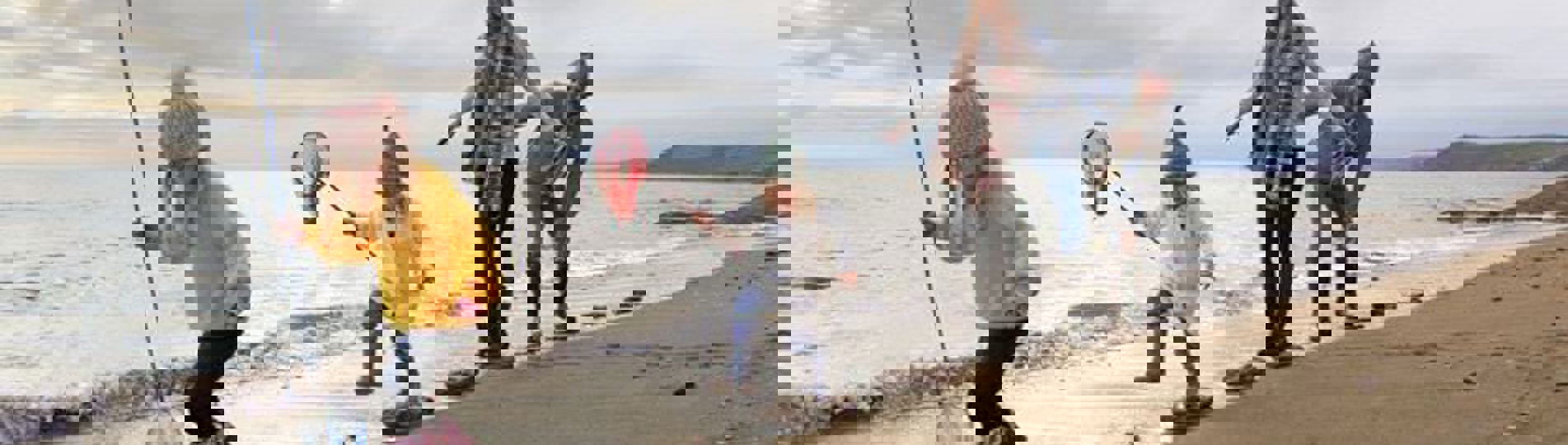 A family of four stepping across stones on the shoreline