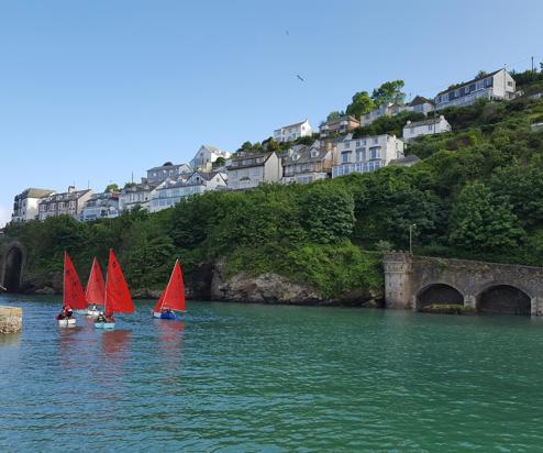 A body of water by land with various boats going out towards the sea