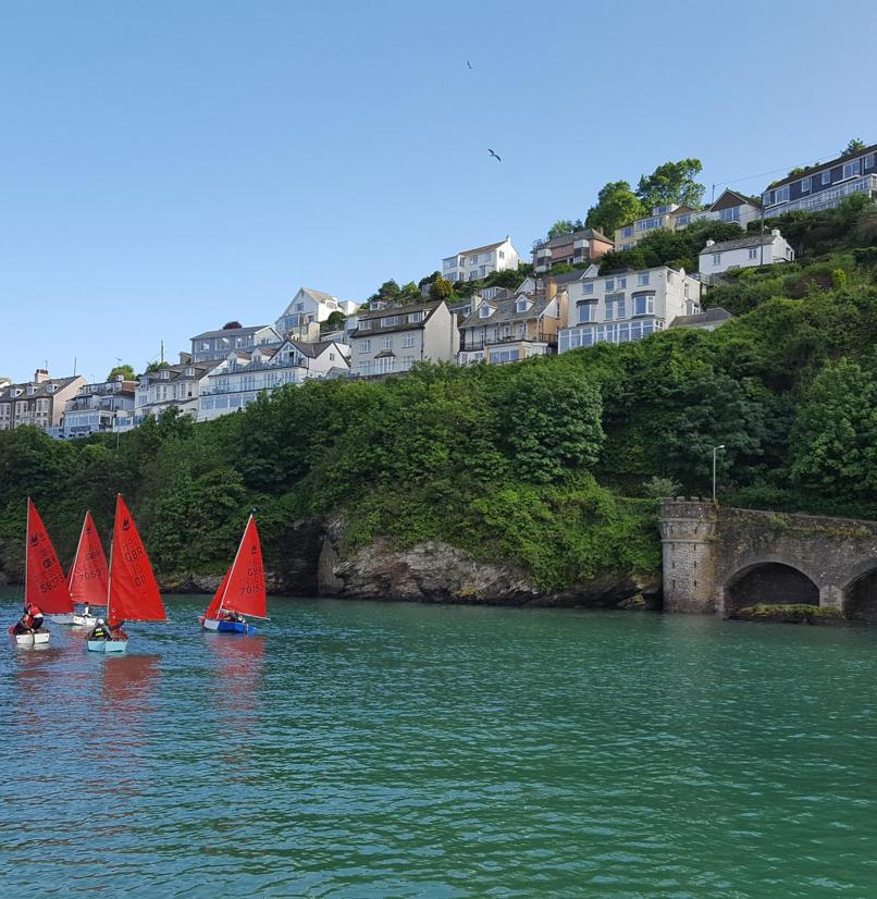 A body of water by land with various boats going out towards the sea