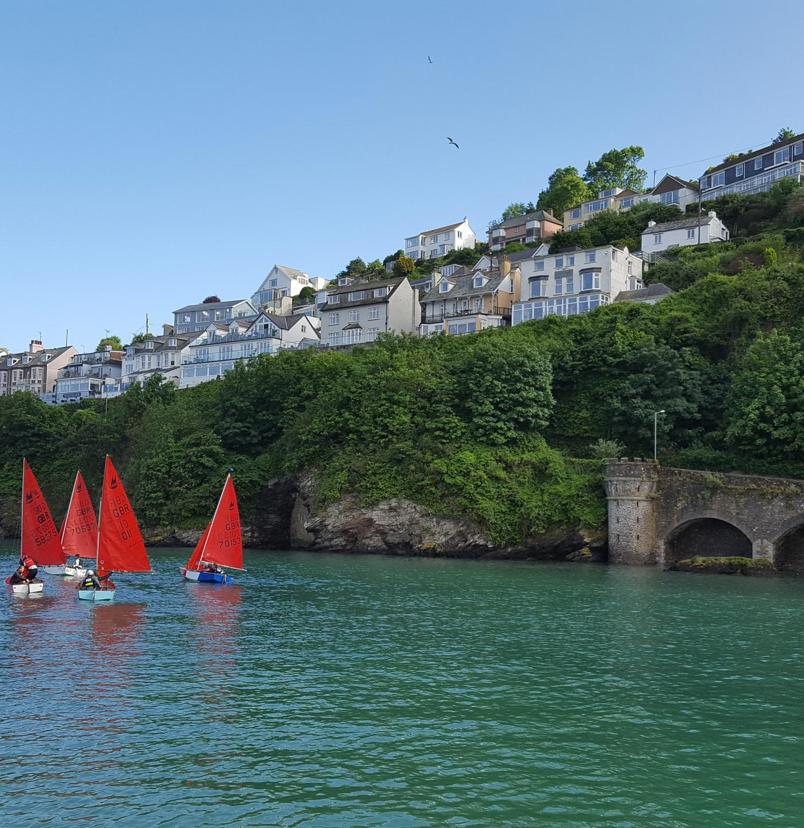 A body of water by land with various boats going out towards the sea