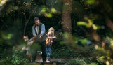 A man and his two young sons fishing by a lake in the woodland 