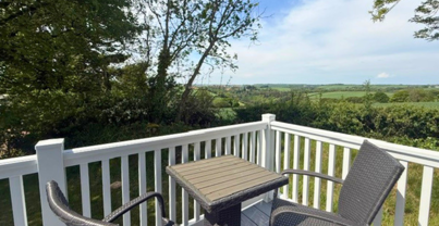 External of a caravan decking with table and chairs and countryside views