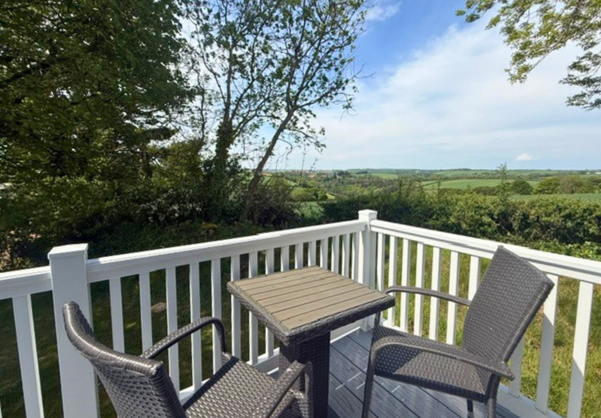 External of a caravan decking with table and chairs and countryside views
