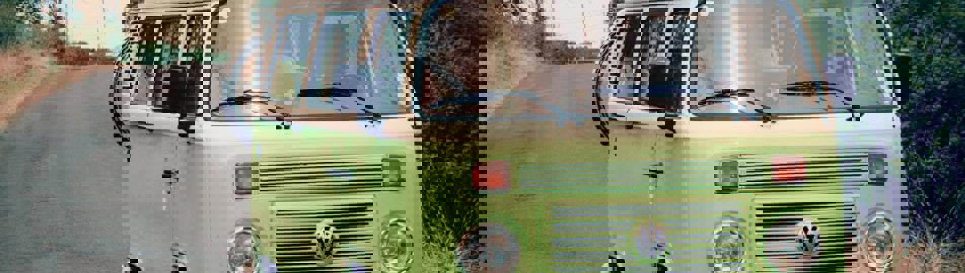 A classic VW old green campervan on the road