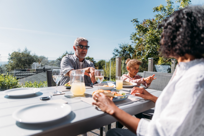 Family sharing a meal on their deck in the sunshine