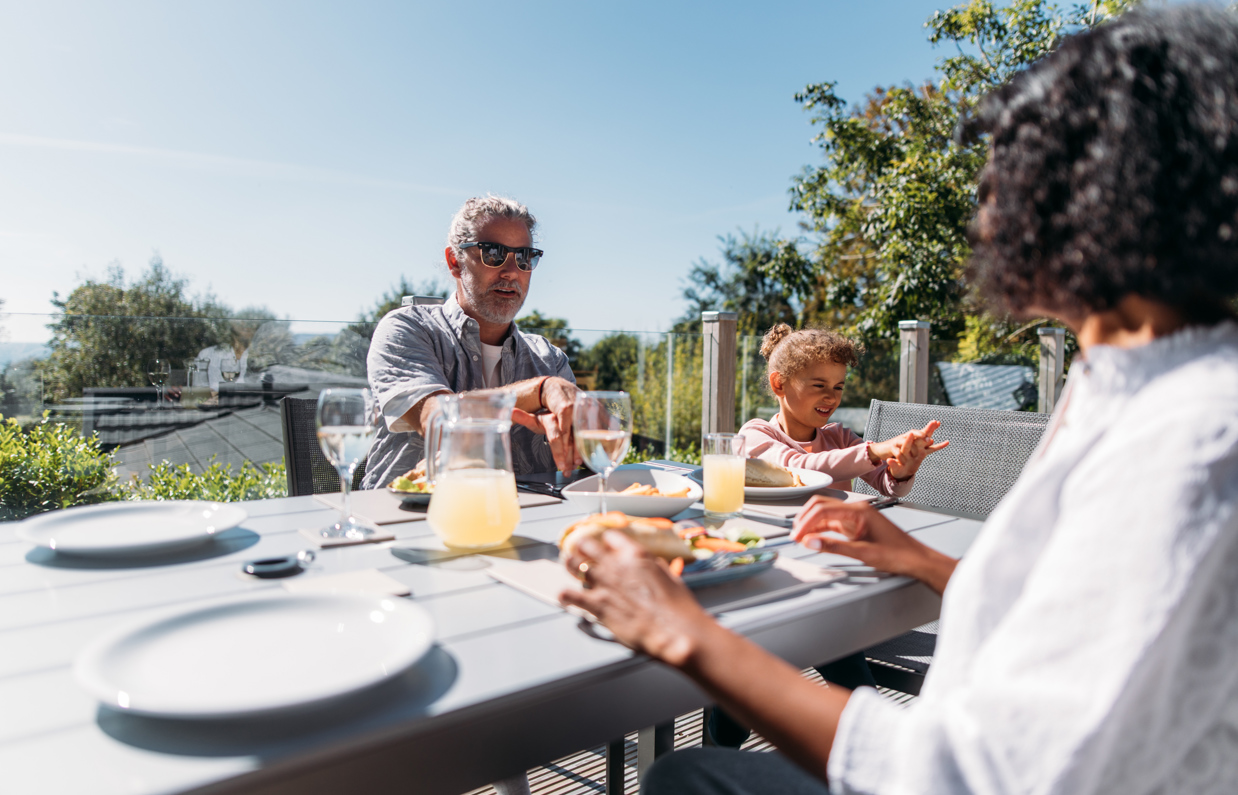 Family sharing a meal on their deck in the sunshine