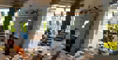 Cosy and contemporary lounge with neutral tones, checked curtains and comfy sofa and armchairs