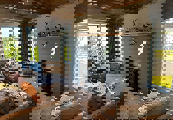 Cosy and contemporary lounge with neutral tones, checked curtains and comfy sofa and armchairs