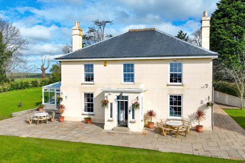 External of a manor house with conservatory, outside seating and grass areas 