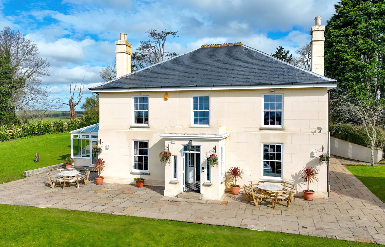 External of a manor house with conservatory, outside seating and grass areas 